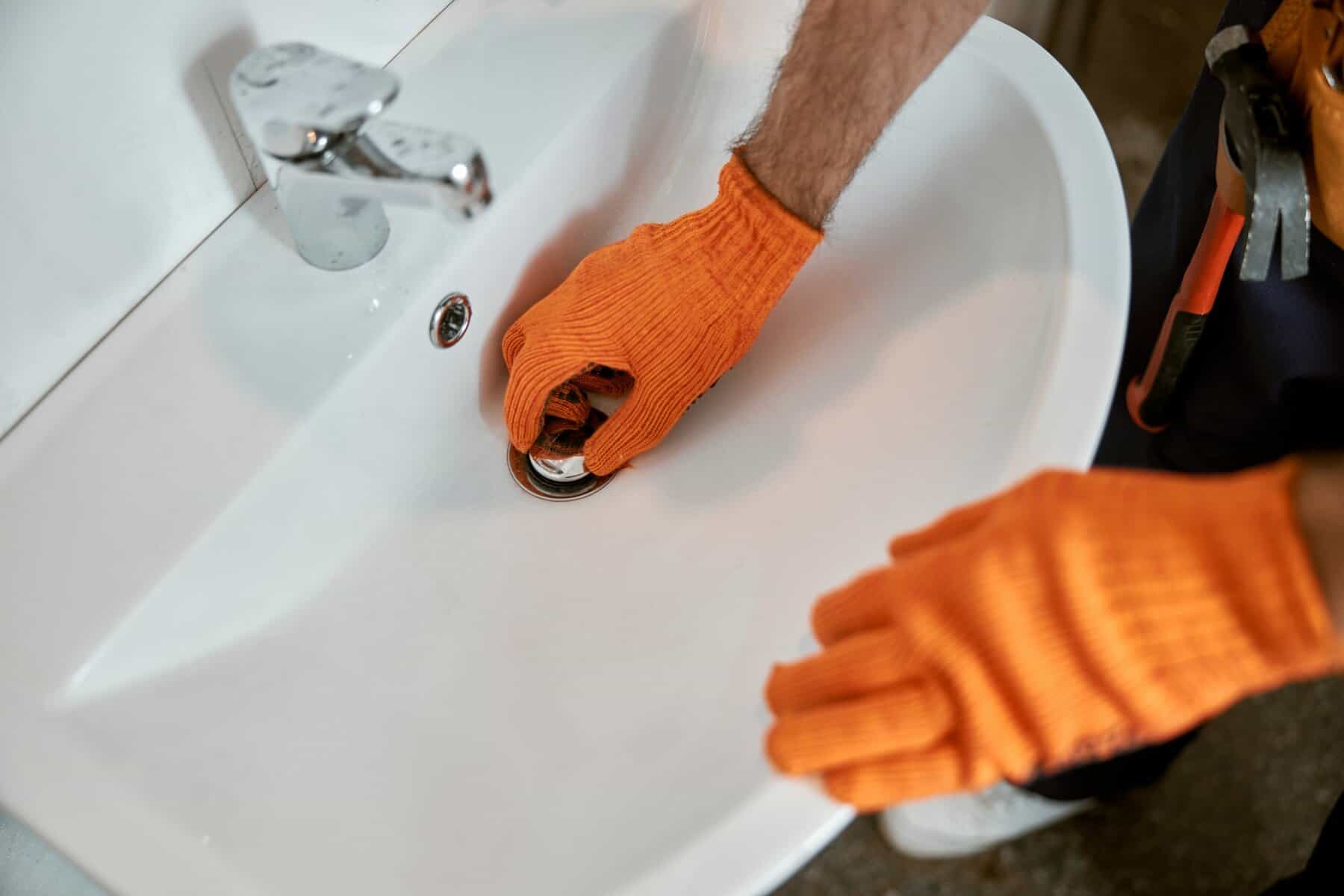 Male plumber hands repairing sink in bathroom